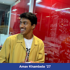 Student standing in front of red board.