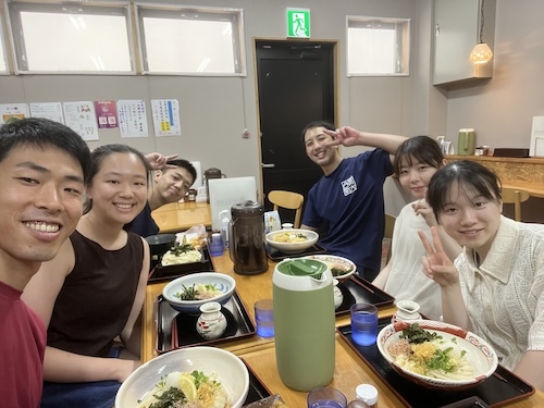 Group of students sitting around a table smiling at the camera.