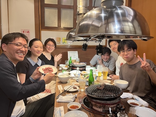 A group of people sitting around a table smiling at the camera.